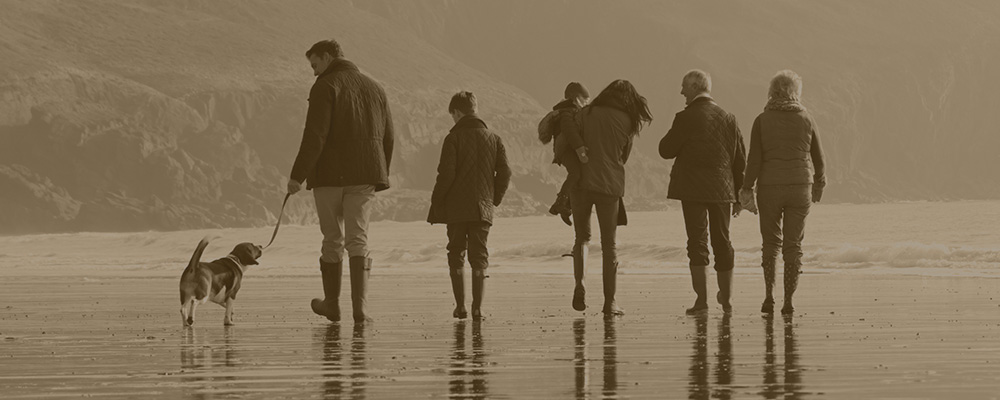 family walking dog on beach